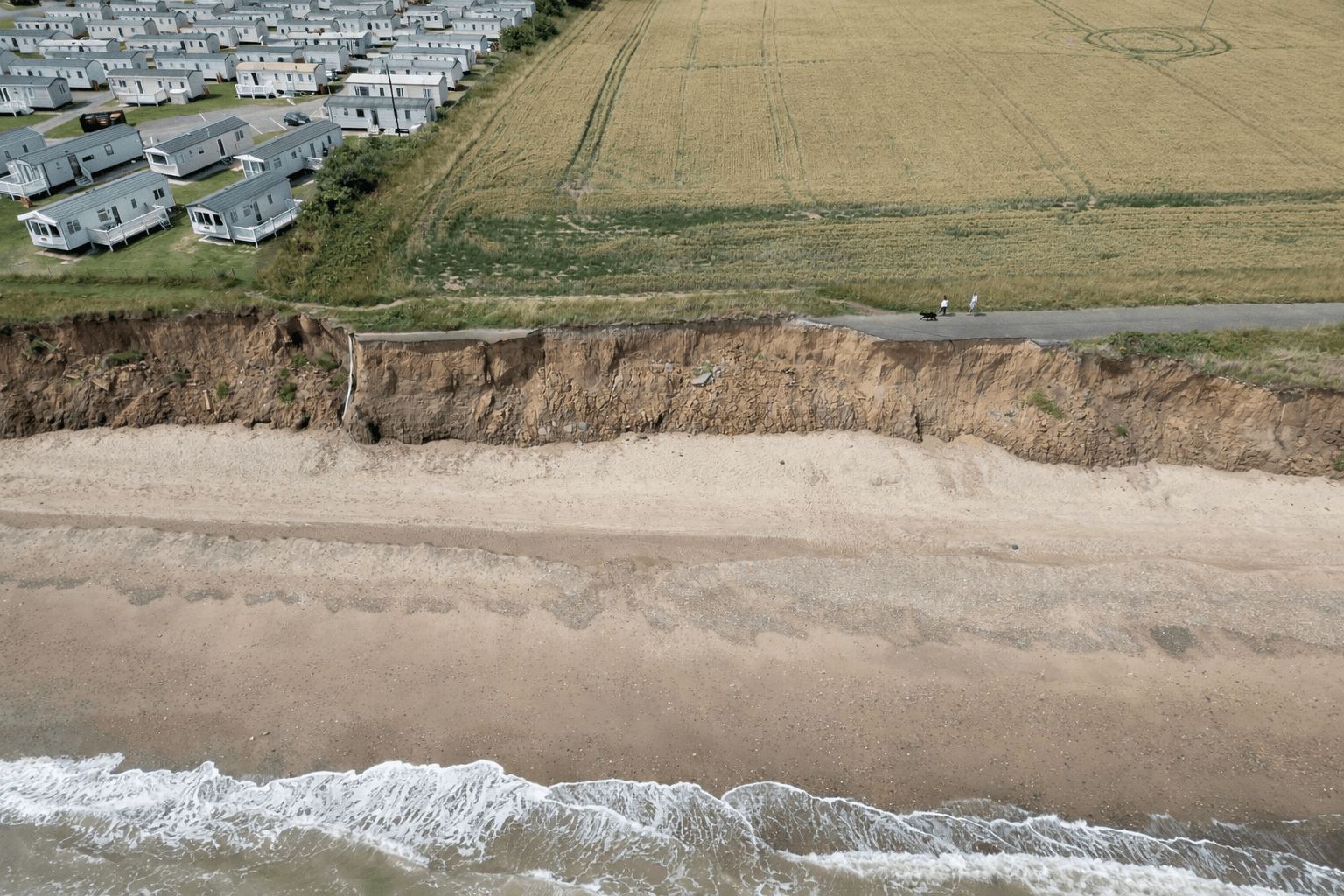 Aerial view of a coastal caravan park near an eroding cliff edge